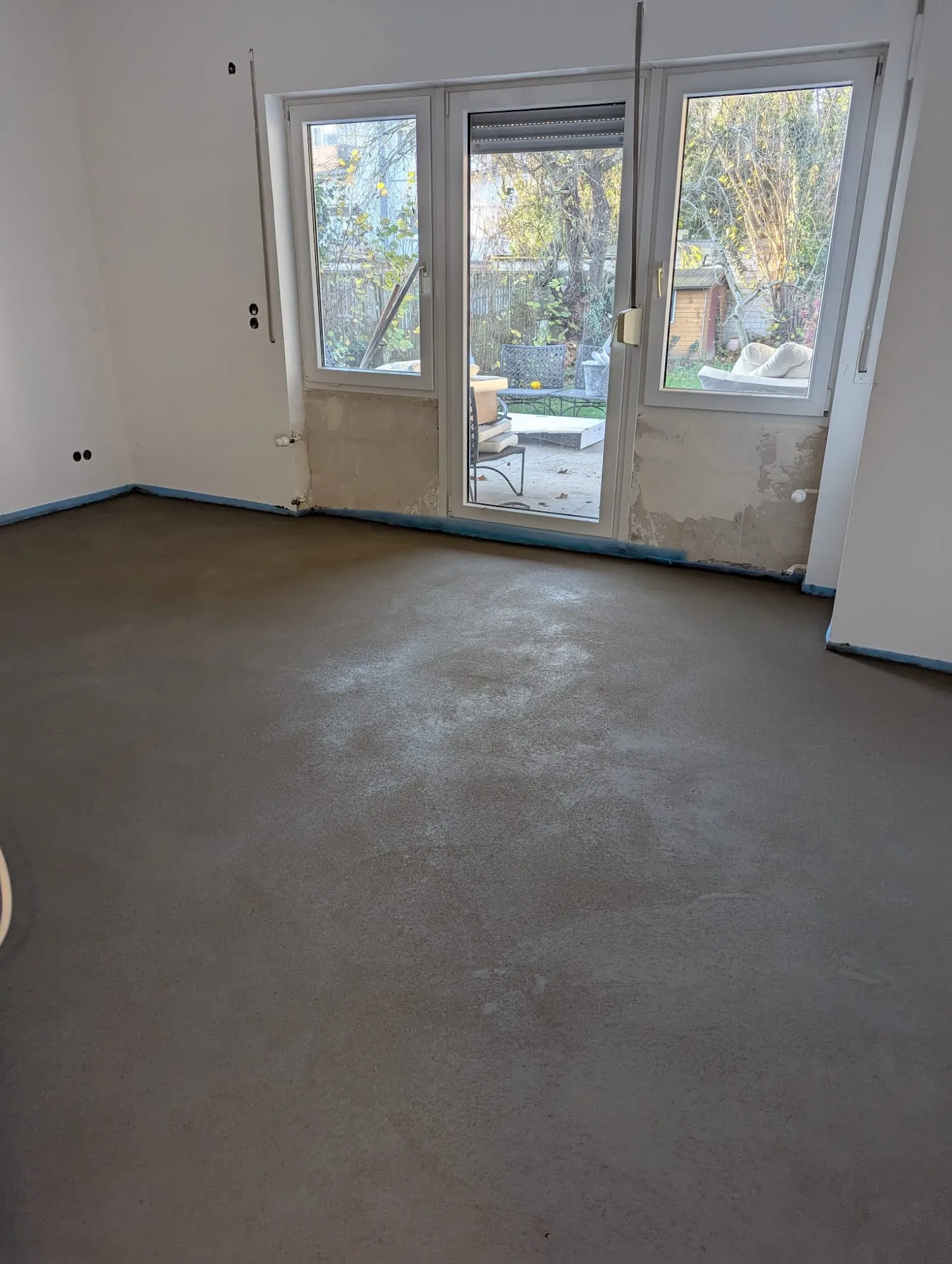 Komplett entkernter Wohnraum mit frisch verlegtem Estrich und neuen Fenstern während einer Sanierung in Beckum