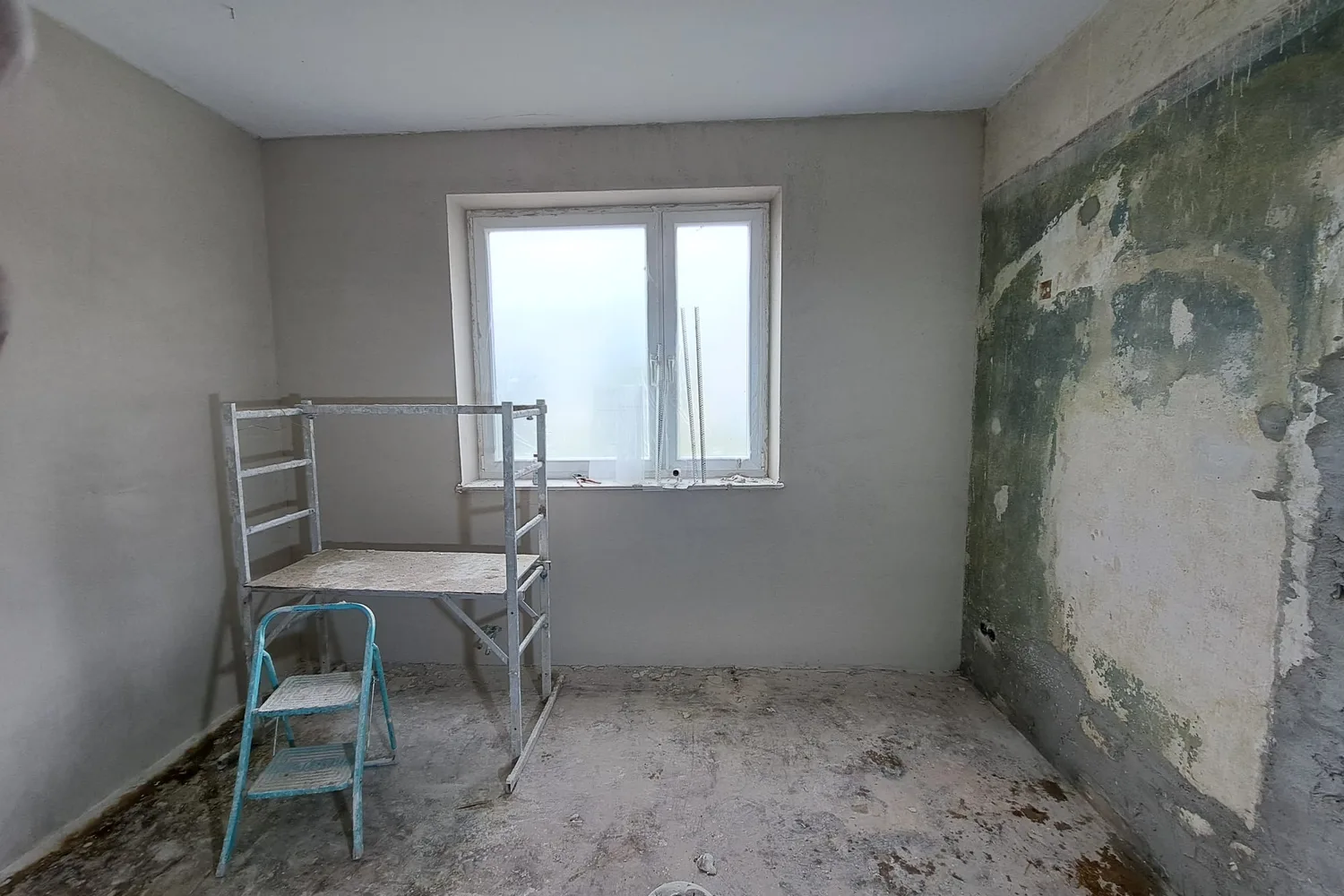Raum während der Putzarbeiten: links die bereits neu verputzte Wand, rechts der alte Untergrund